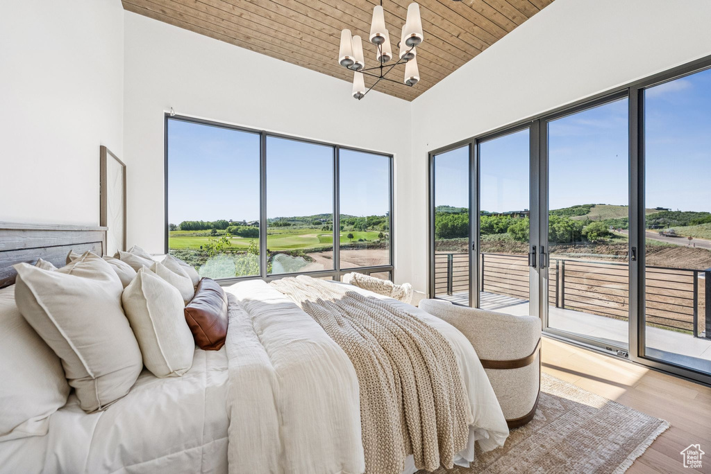Bedroom featuring a chandelier, access to outside, wooden ceiling, wood finished floors, and view of golf course