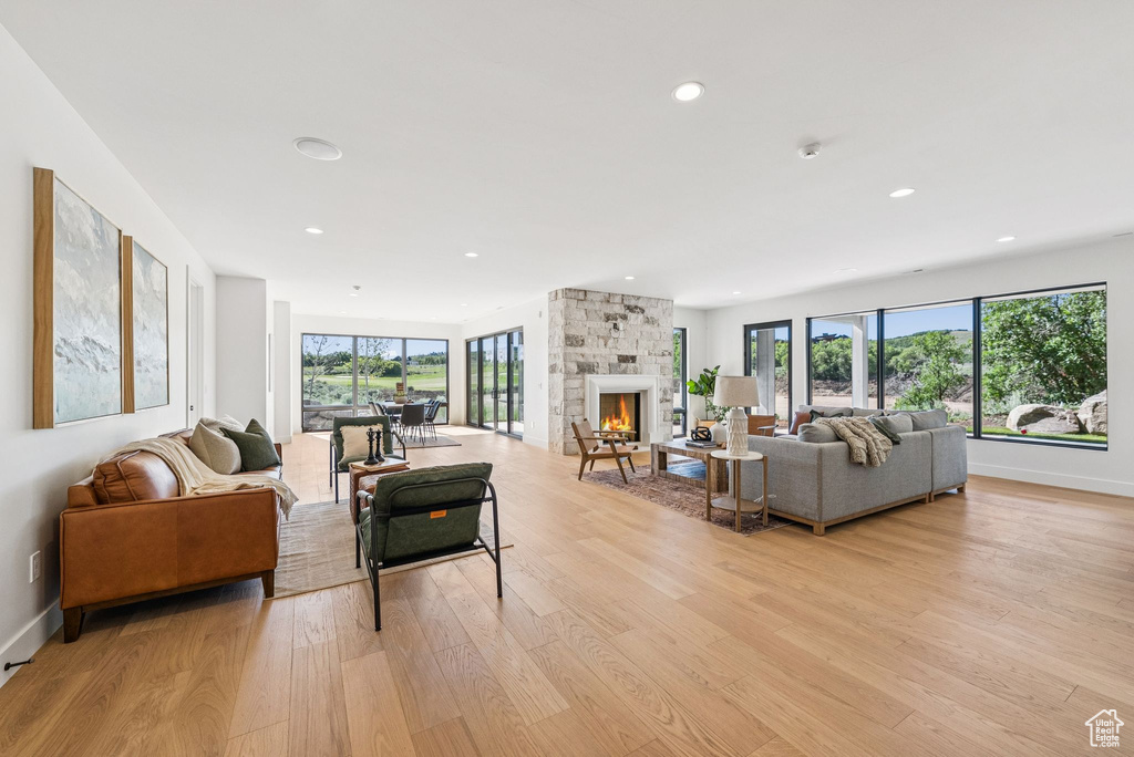 Living area with light wood-type flooring, a stone fireplace, and recessed lighting