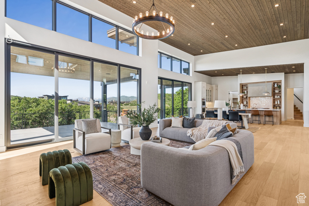 Living room featuring wooden ceiling, recessed lighting, a towering ceiling, light wood finished floors, and a chandelier