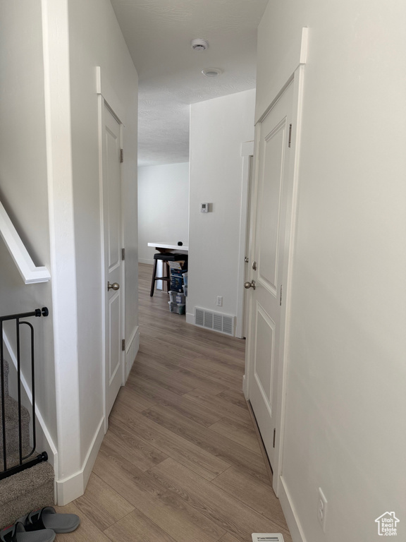 Corridor with light wood-type flooring and baseboards
