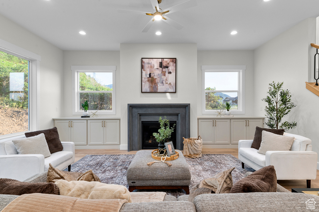 Living room featuring light wood-type flooring, recessed lighting, a fireplace, and ceiling fan
