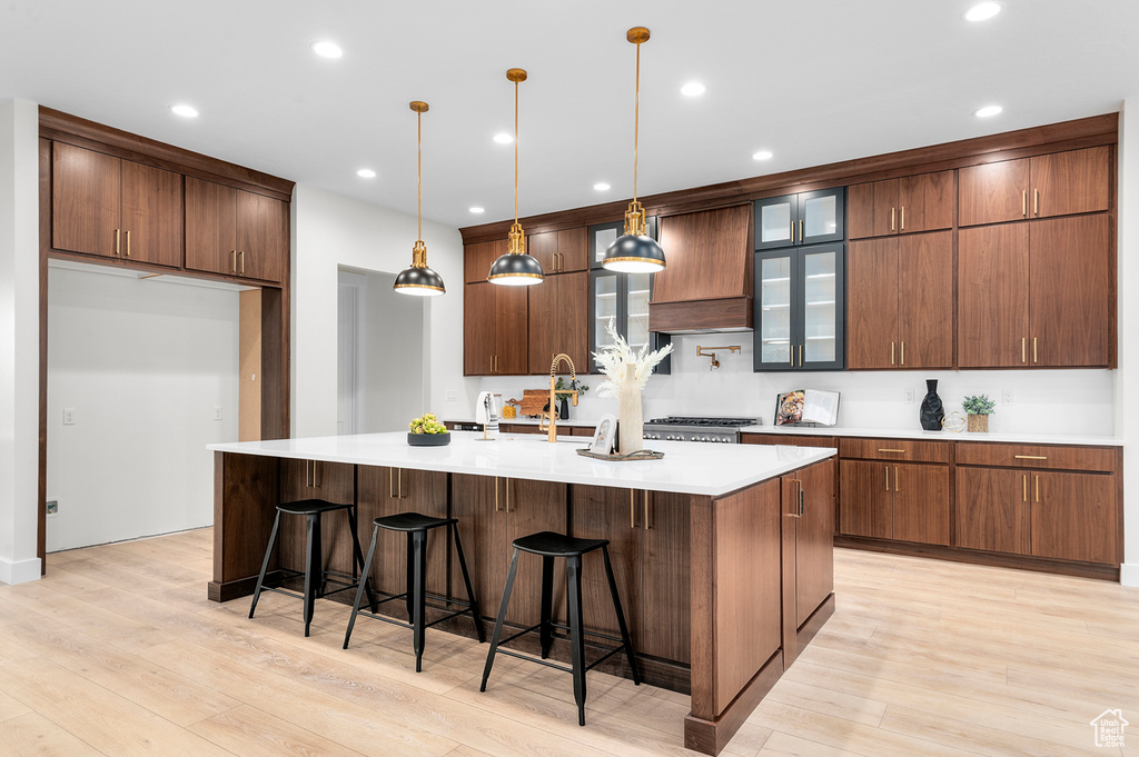 Kitchen with light wood-style flooring, a large island, light countertops, a breakfast bar, and decorative light fixtures