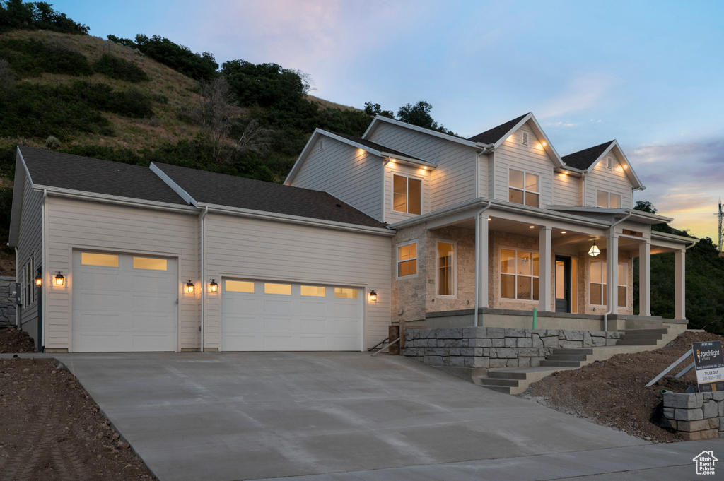 View of front of house featuring a garage, driveway, and covered porch