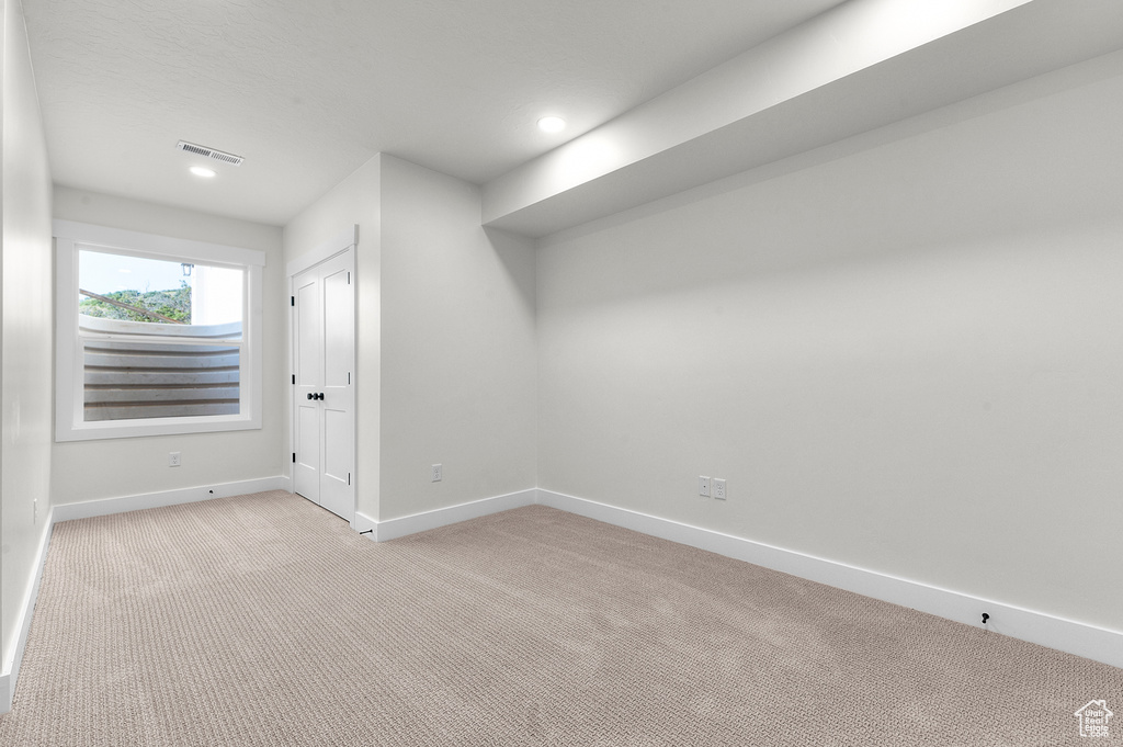 Unfurnished room with light colored carpet and recessed lighting