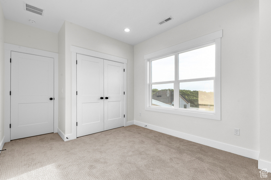 Unfurnished bedroom featuring light carpet, a closet, and recessed lighting