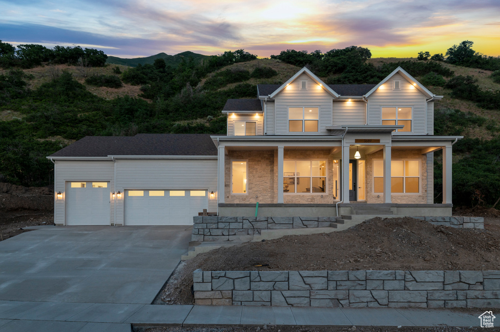 View of front of property with covered porch, concrete driveway, and an attached garage