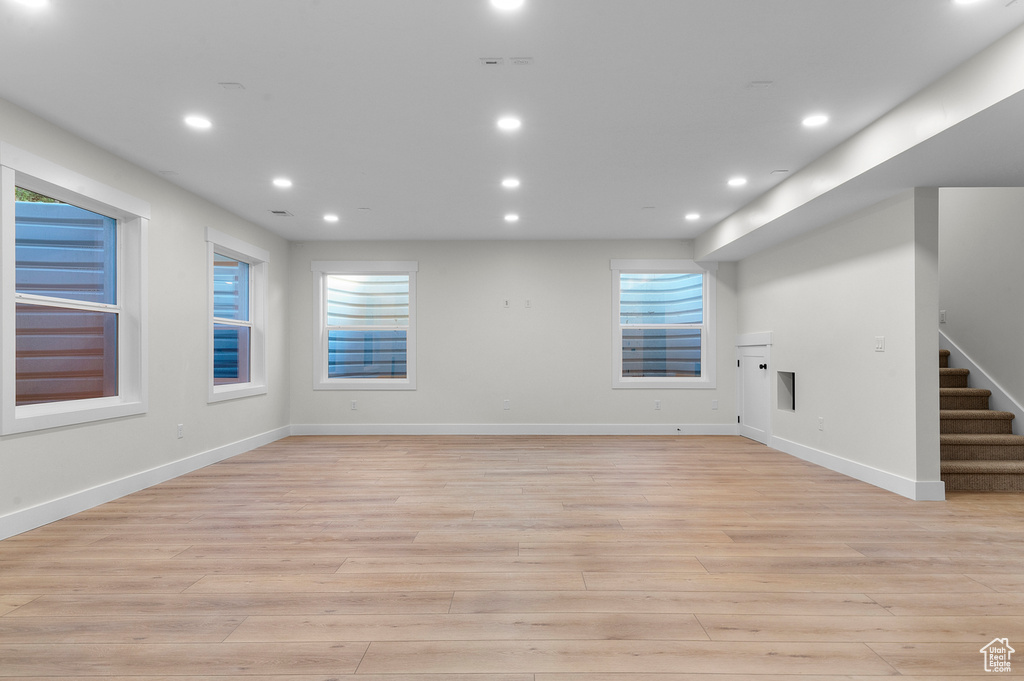 Unfurnished living room with light wood-type flooring, stairway, and recessed lighting