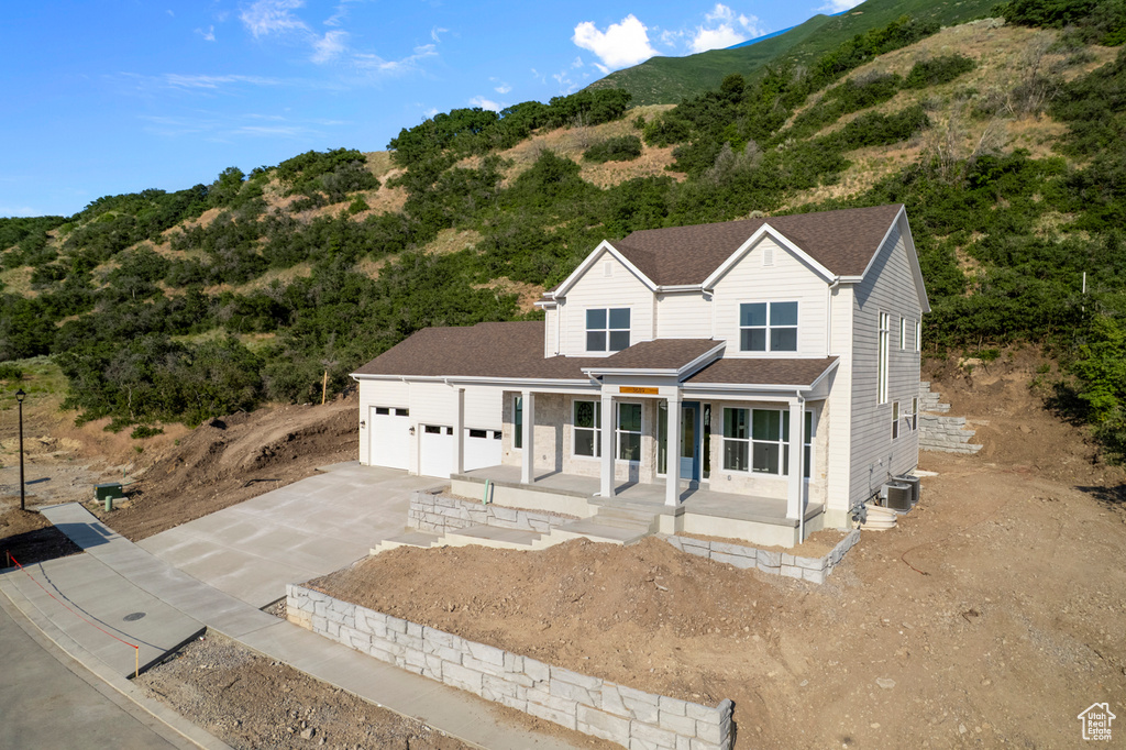 View of front of property featuring driveway, a porch, a mountain view, roof with shingles, and a garage