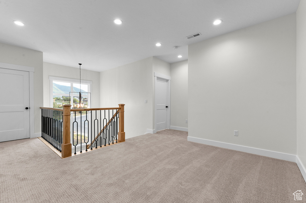 Empty room with carpet flooring, recessed lighting, and a chandelier