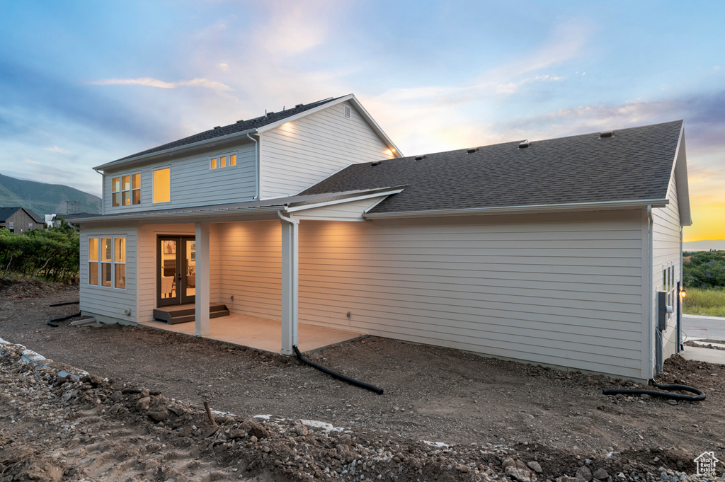 Back of house featuring french doors, a patio, a shingled roof, and a mountain view