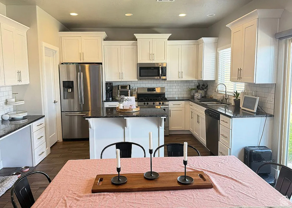 Kitchen with appliances with stainless steel finishes, tasteful backsplash, dark wood finished floors, white cabinetry, and recessed lighting