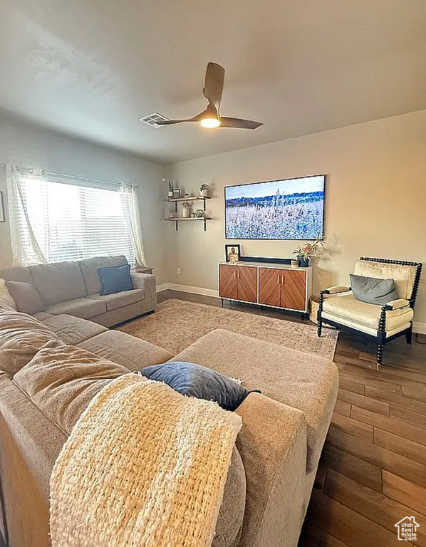 Living area featuring dark wood-style flooring and a ceiling fan