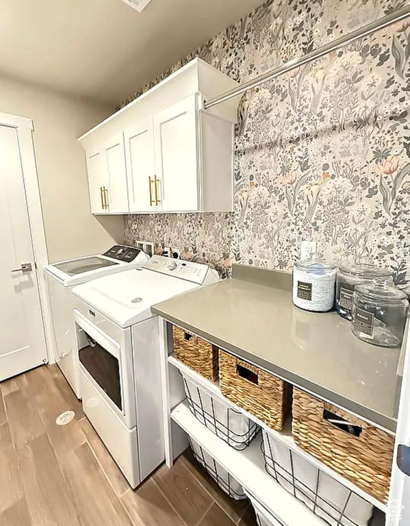 Laundry area with cabinet space, washing machine and dryer, and light wood-style floors
