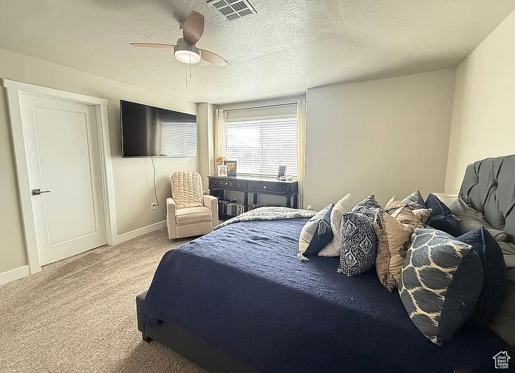 Carpeted bedroom featuring a ceiling fan and a textured ceiling