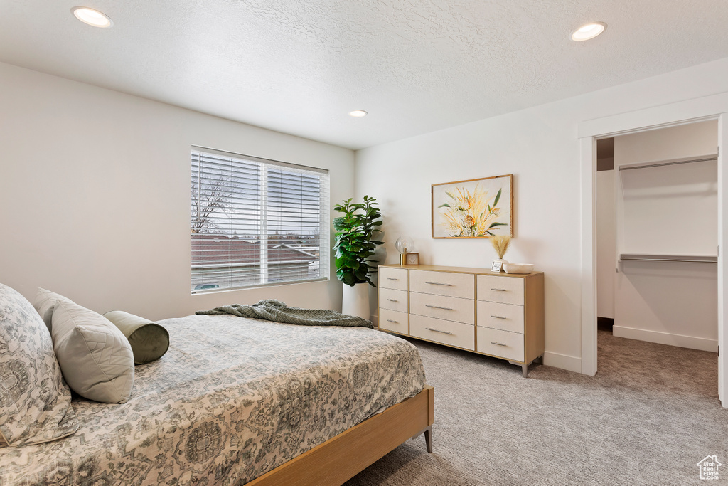 Bedroom featuring light colored carpet, recessed lighting, and a walk in closet