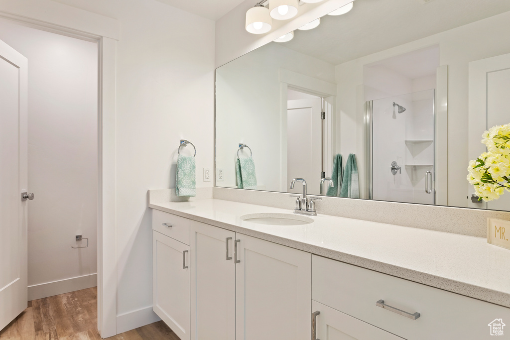 Full bath with wood finished floors, vanity, and a shower stall