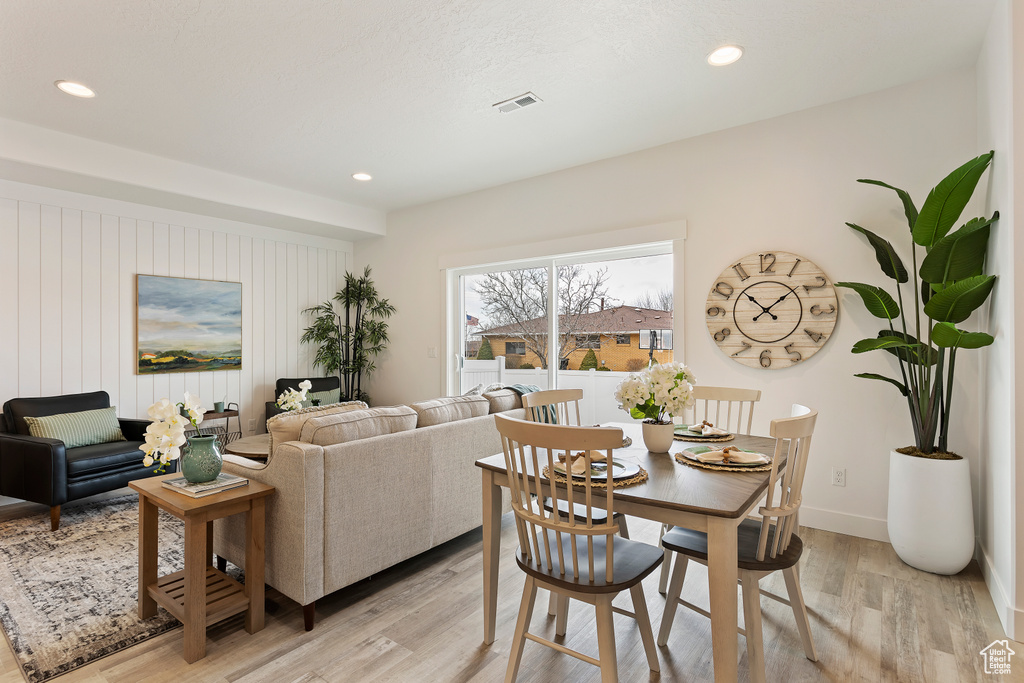 Dining room with light wood finished floors and recessed lighting