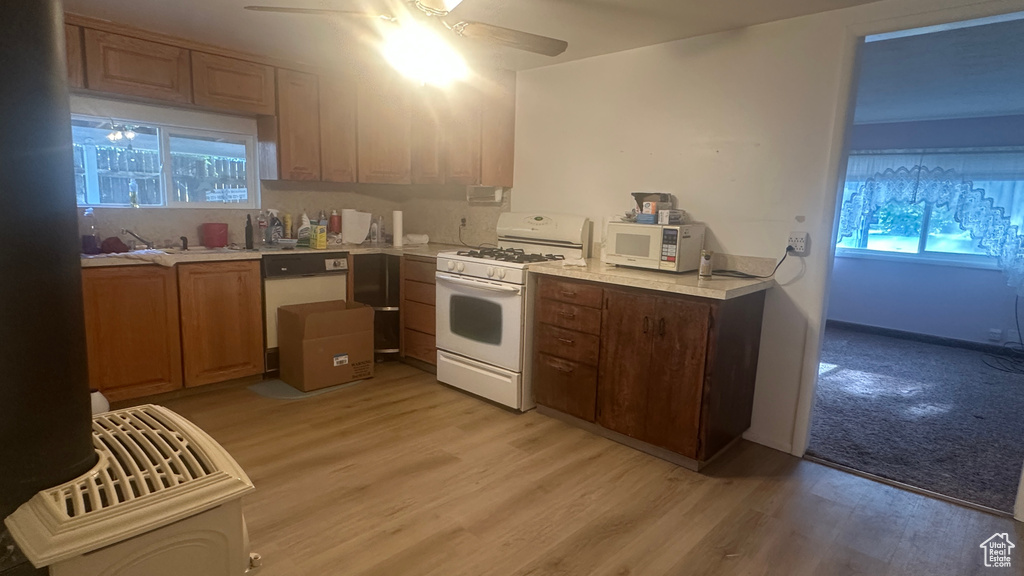 Kitchen featuring white appliances, ceiling fan, light wood-type flooring, and light countertops