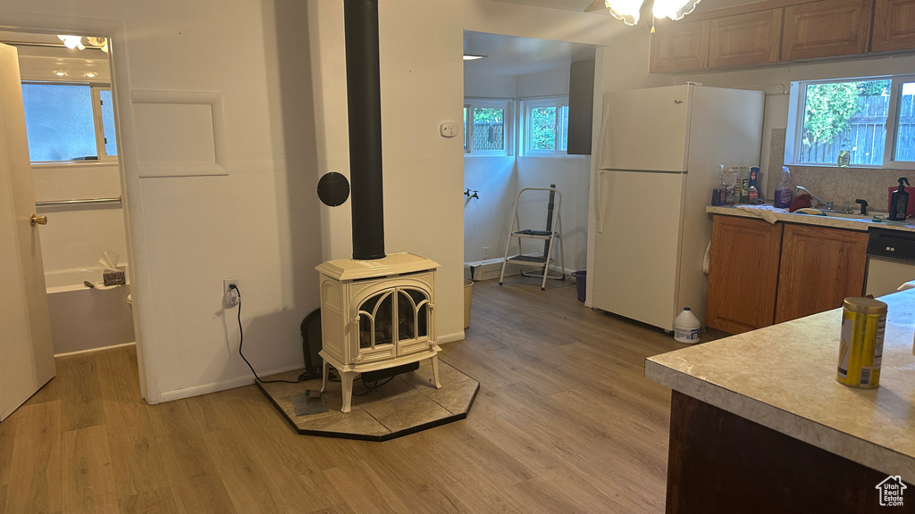 Kitchen with white appliances, a wood stove, light wood-style flooring, and light countertops