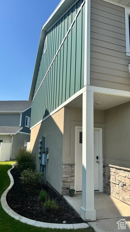 View of side of home featuring board and batten siding, stucco siding, and stone siding