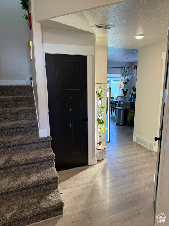 Entryway with stairs, a textured ceiling, and light wood finished floors