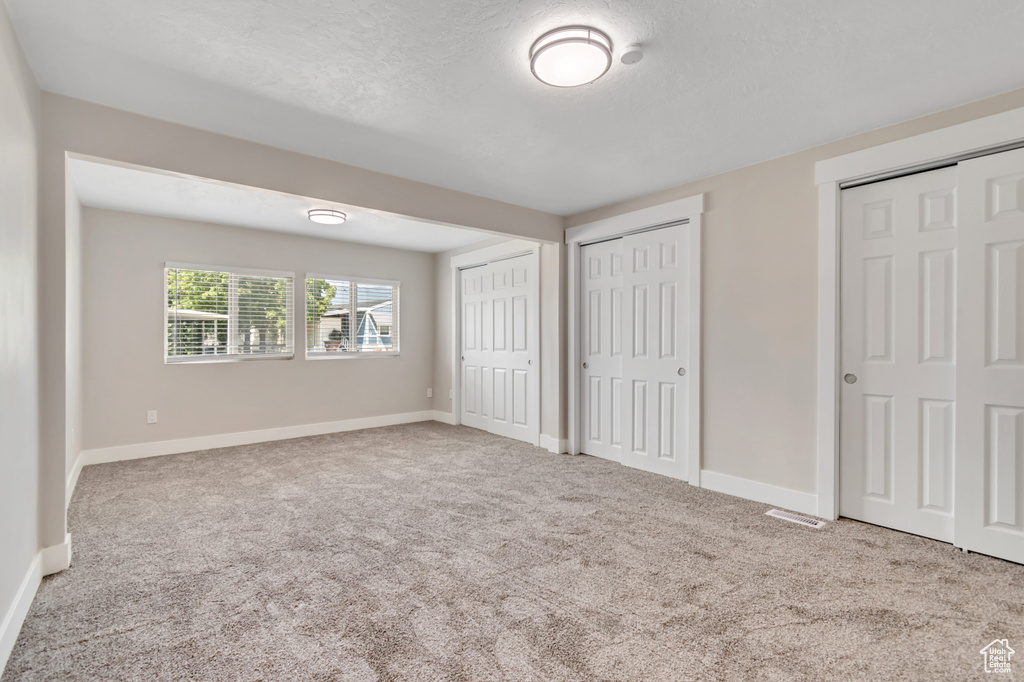 Unfurnished bedroom featuring two closets and carpet flooring