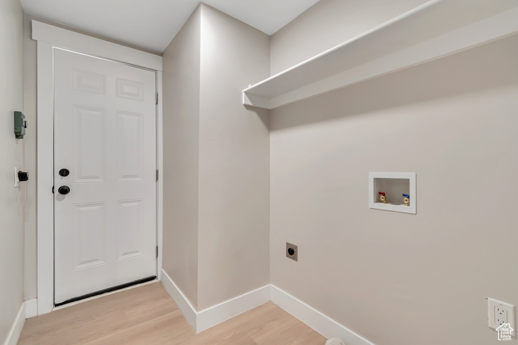 Washroom with hookup for an electric dryer, light wood-style flooring, and hookup for a washing machine
