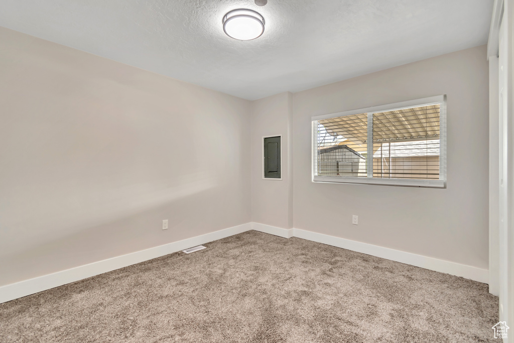 Carpeted spare room featuring baseboards and a textured ceiling