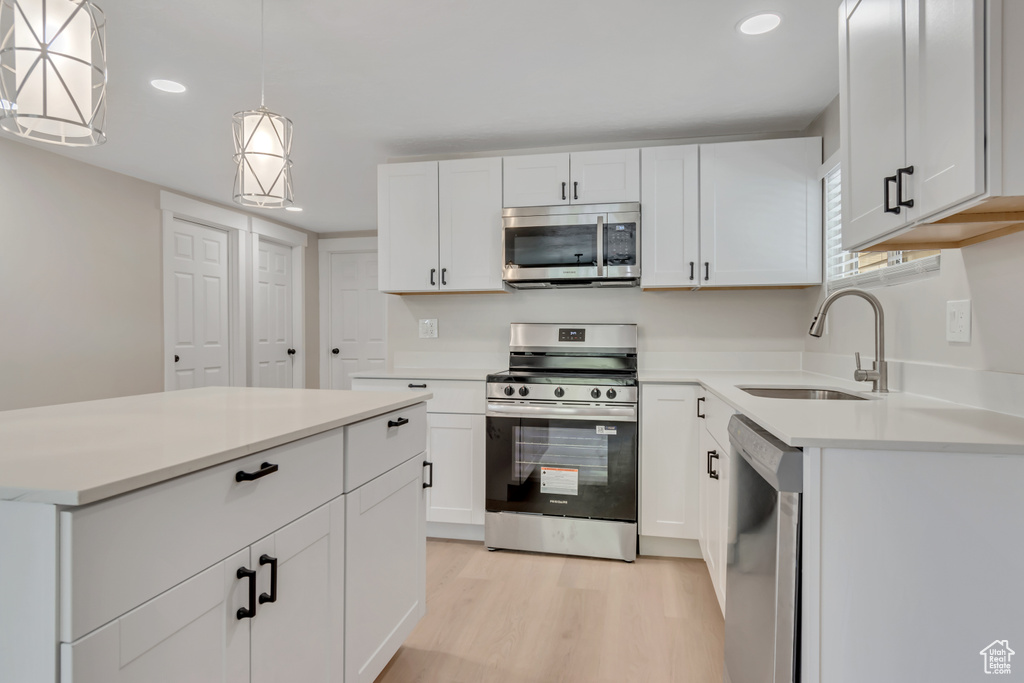 Kitchen with appliances with stainless steel finishes, light wood-type flooring, recessed lighting, light countertops, and white cabinetry