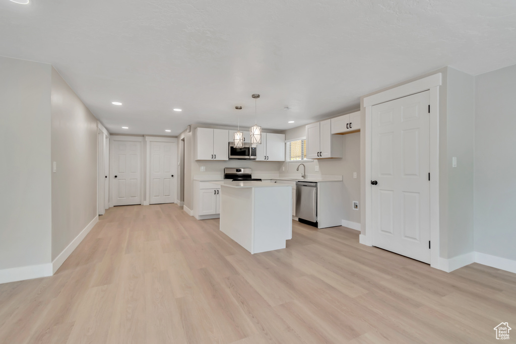 Kitchen featuring stainless steel appliances, white cabinetry, recessed lighting, light wood-style flooring, and a kitchen island