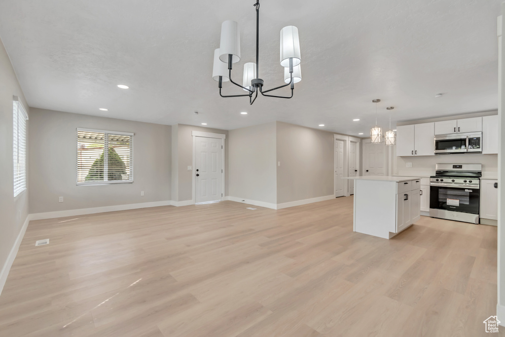 Kitchen featuring stainless steel appliances, a chandelier, a center island, white cabinets, and light wood-type flooring