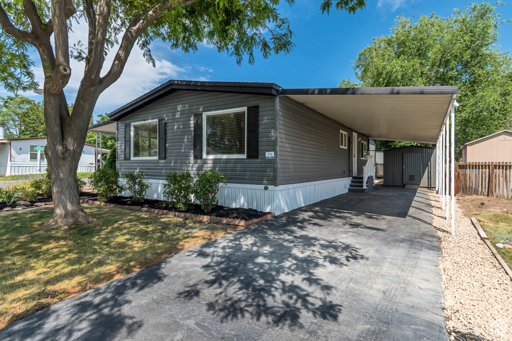 Manufactured / mobile home with driveway, a carport, an outdoor structure, and entry steps