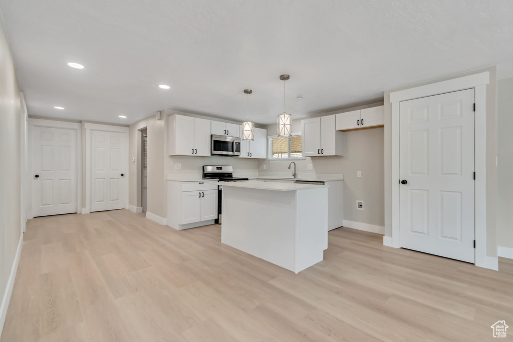 Kitchen featuring appliances with stainless steel finishes, white cabinets, light wood-style flooring, light countertops, and recessed lighting