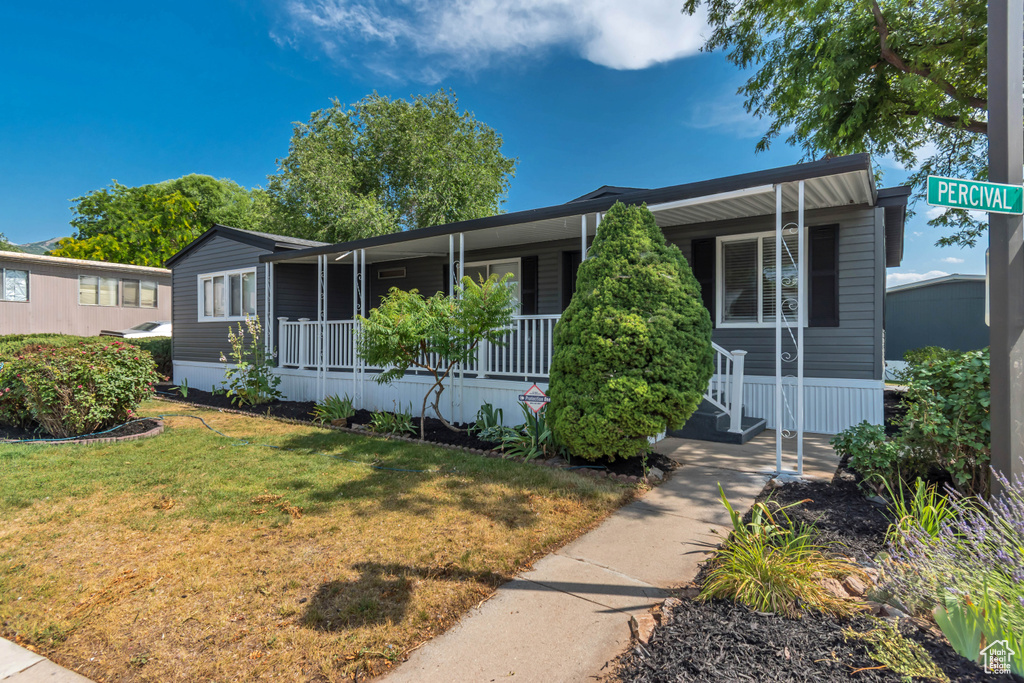 Manufactured / mobile home with covered porch and a front lawn