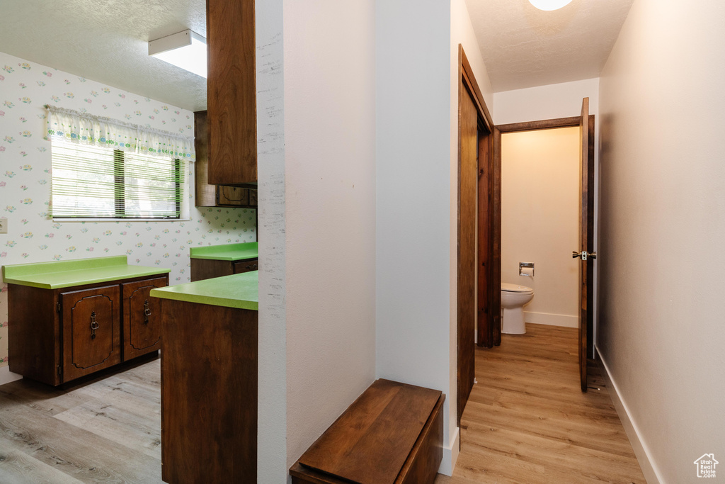 Corridor with light wood-style flooring and wallpapered walls