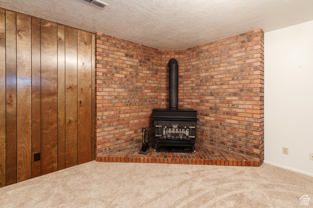 Detailed view of carpet, a wood stove, and a textured ceiling