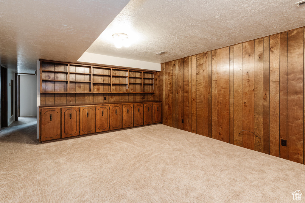 Finished basement featuring carpet floors, wooden walls, and a textured ceiling
