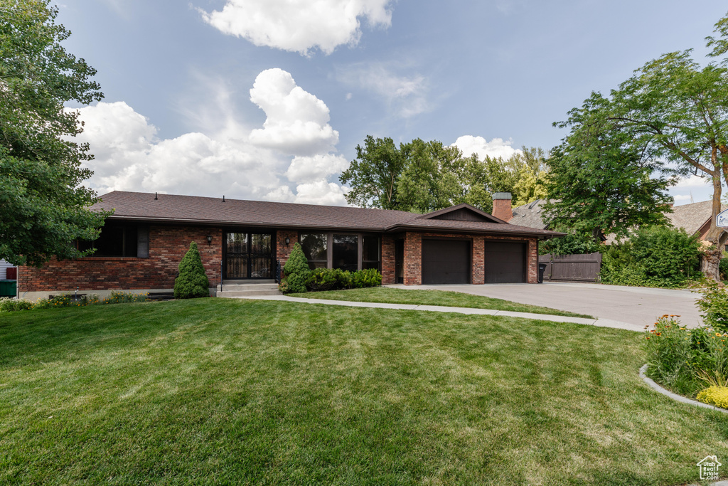 View of front of house featuring brick siding, an attached garage, driveway, and a chimney