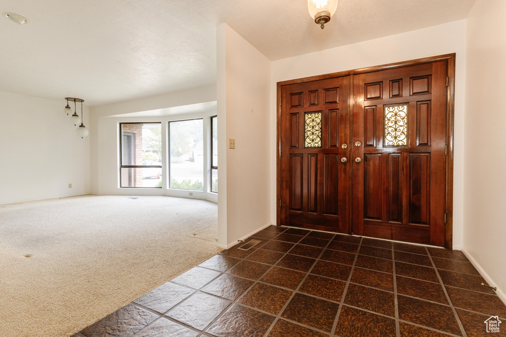 Foyer featuring dark colored carpet and baseboards