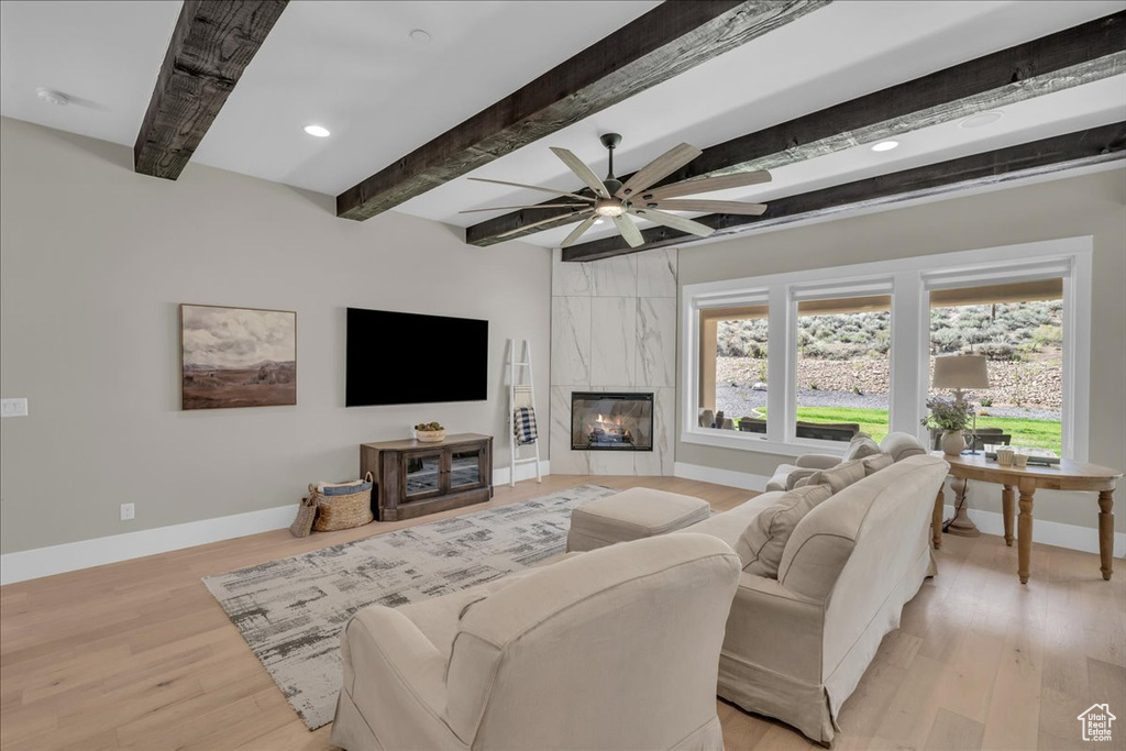 Living area with beam ceiling, a ceiling fan, light wood finished floors, a fireplace, and recessed lighting