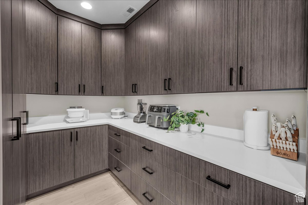 Kitchen featuring light countertops, dark brown cabinetry, and light wood finished floors