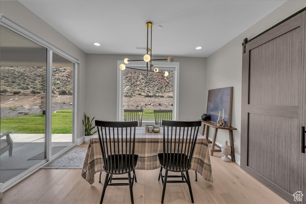 Dining room with light wood-type flooring, healthy amount of natural light, a barn door, and recessed lighting