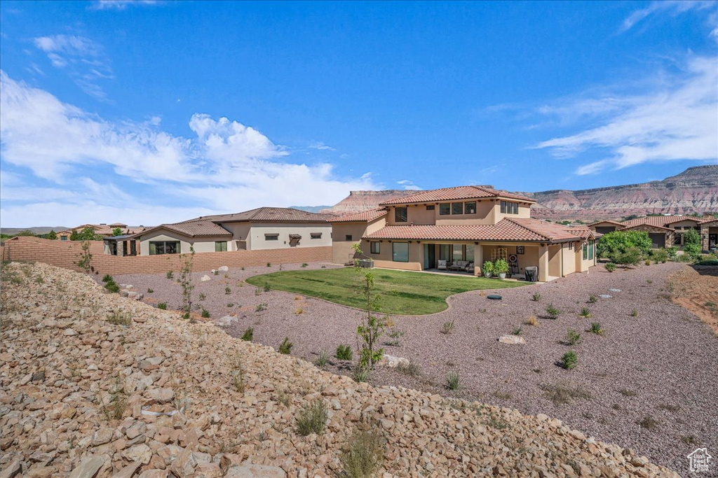 Back of house featuring a tile roof, stucco siding, an attached garage, and a mountain view