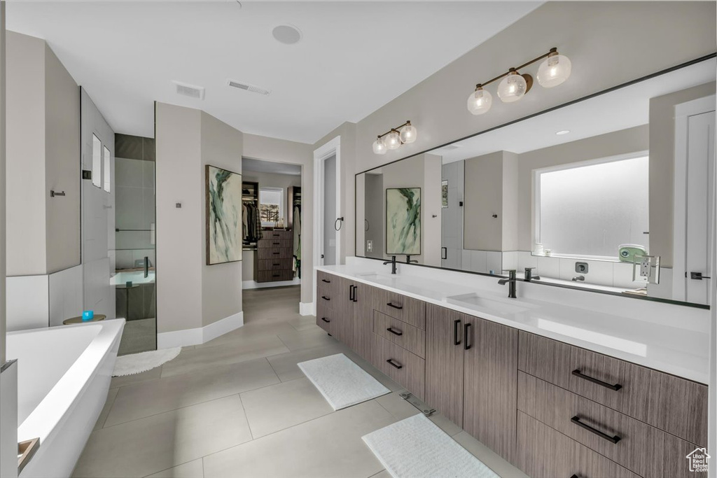 Full bathroom featuring a freestanding tub, double vanity, tiled shower, and tile patterned floors