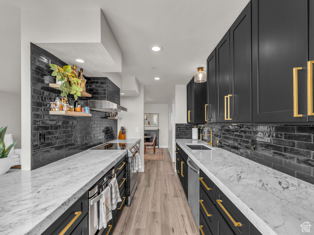 Kitchen featuring appliances with stainless steel finishes, backsplash, light wood finished floors, light stone countertops, and recessed lighting