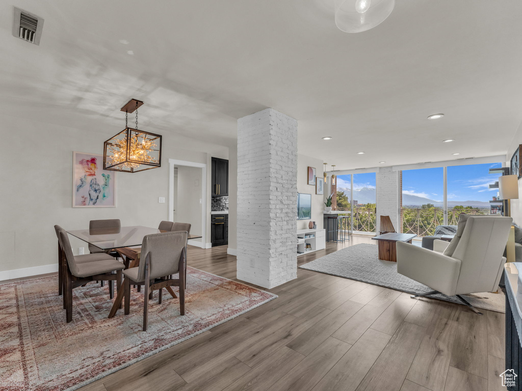 Dining space featuring wood finished floors, recessed lighting, a fireplace, a wall of windows, and a chandelier