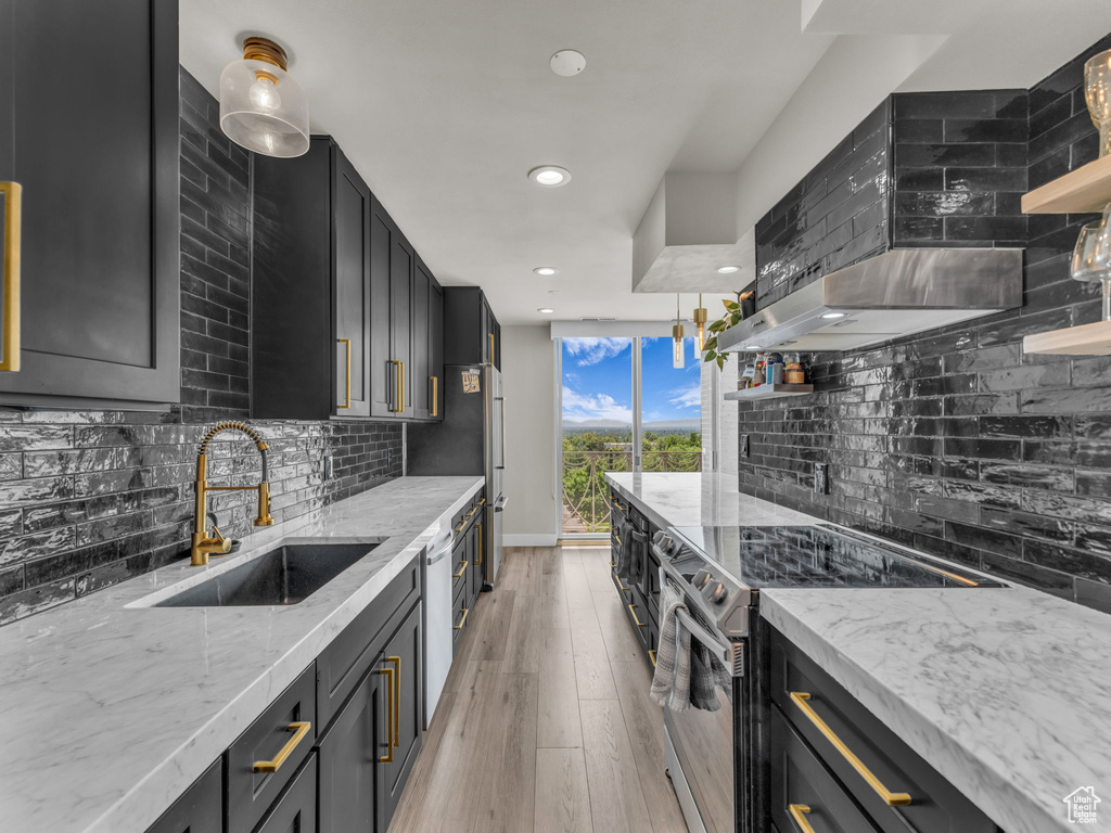 Kitchen featuring stainless steel electric range, tasteful backsplash, dark cabinets, wall chimney exhaust hood, and recessed lighting