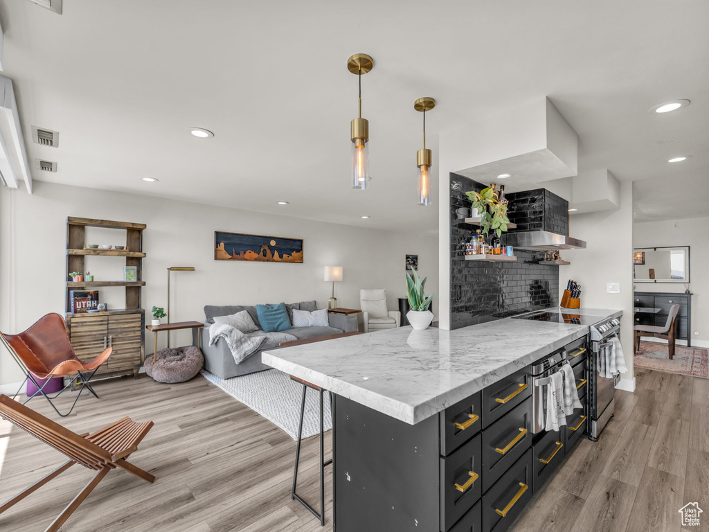 Kitchen with light wood-type flooring, stainless steel electric range, open shelves, recessed lighting, and decorative light fixtures