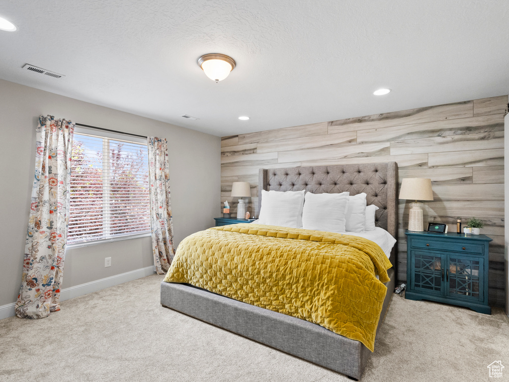 Carpeted bedroom with an accent wall and recessed lighting