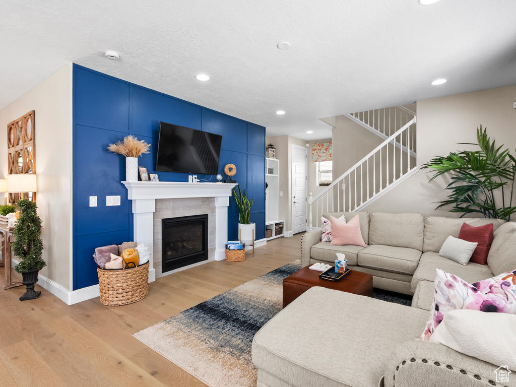 Living area with stairs, light wood-type flooring, recessed lighting, and a glass covered fireplace